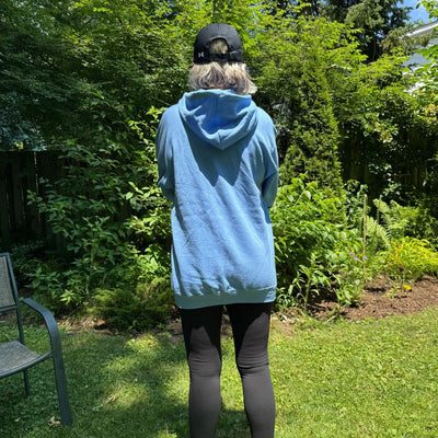 Backside view of women wearing a blue zip up hoodie.