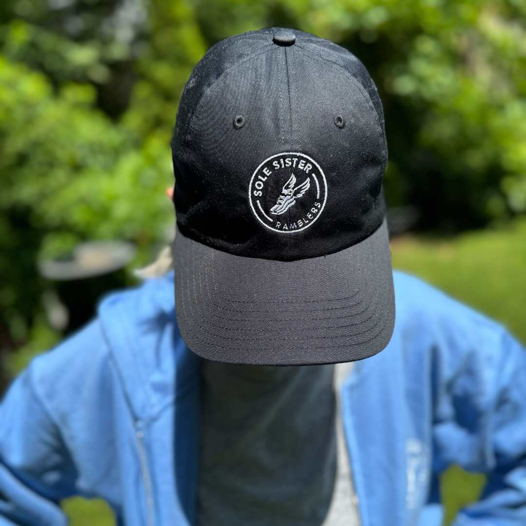 Logo view of women wearing black dad cap with Sole Sister Ramblers logo.