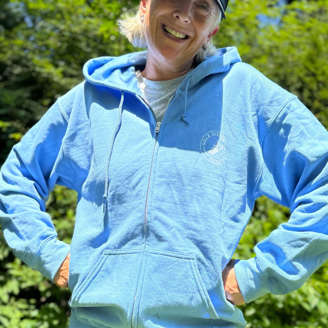 Woman wearing a light blue zip up hoodie with Sole Sister Ramblers log on it.