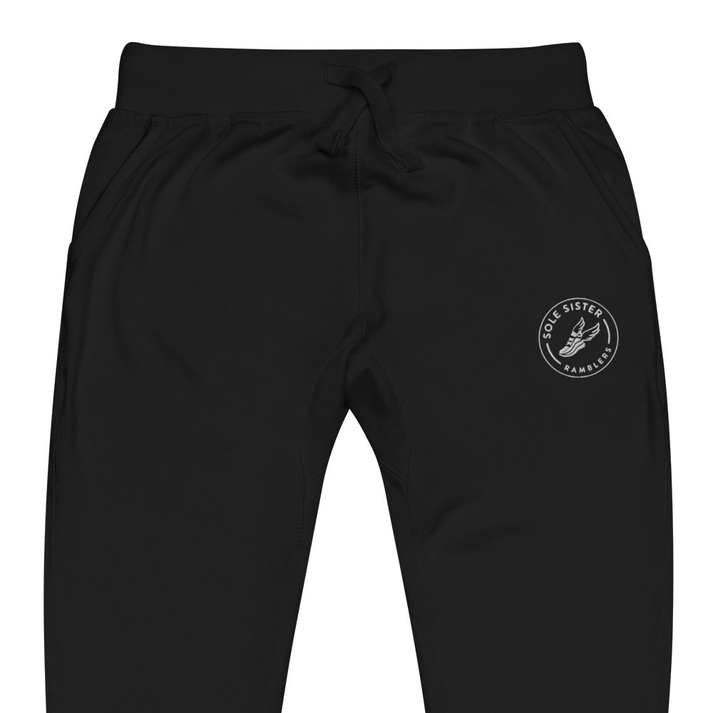 Front view of top of black sweatpants with round Sole Sister Ramblers logo on top leg.